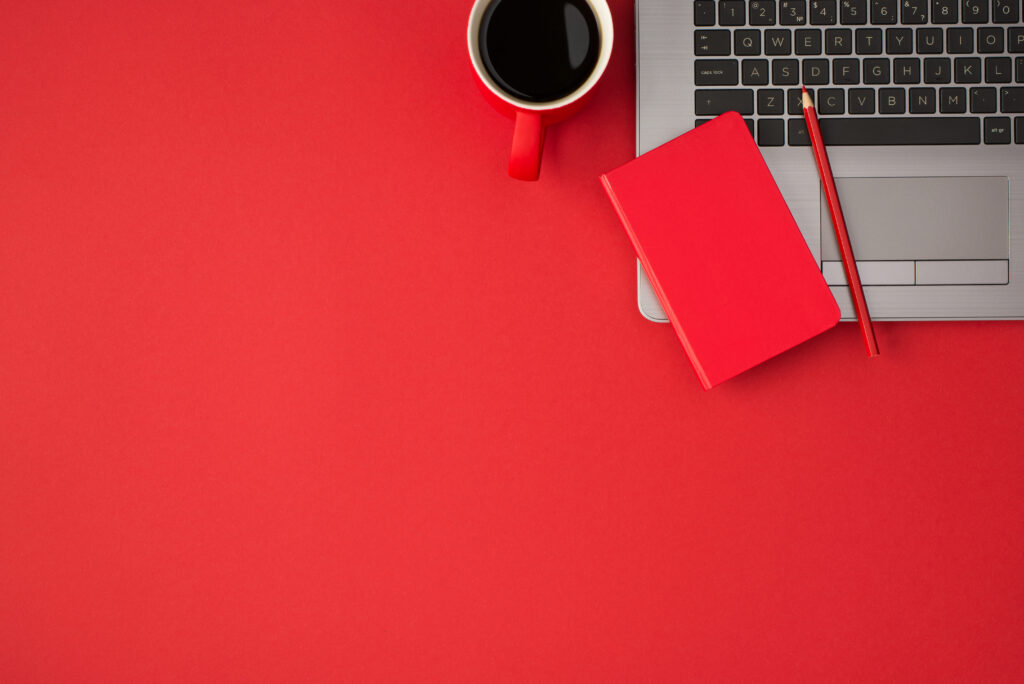 Top view photo of red closed reminder pencil on laptop and cup o